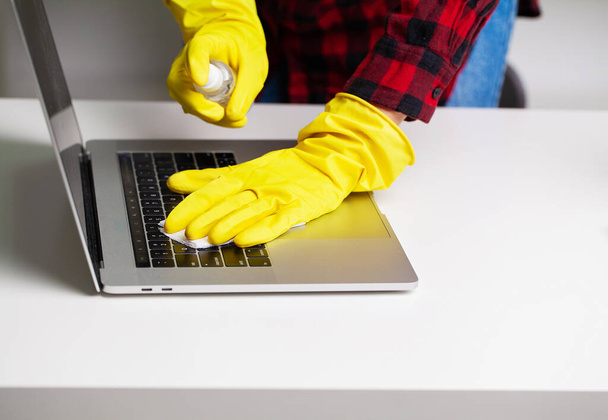 Κοντινό πλάνο του καθαριστή σε κίτρινα γάντια σκουπίζει σκόνη στο γραφείο - Φωτογραφία, εικόνα