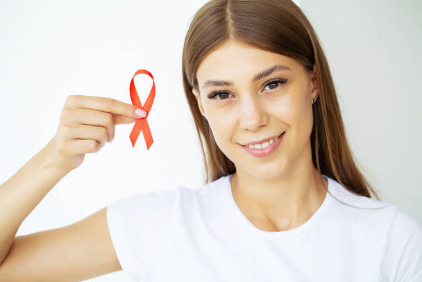 A woman holding a red ribbon emerges from a critical situation after overcoming AIDS - Foto, immagini