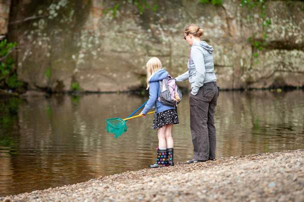 Una madre e una figlia con reti da pesca sul bordo di un fiume. - Foto, immagini