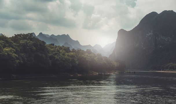 Stunning karst mountain scenery on the riverbank of the magnificent Li river near Yangshuo on a hot summer day, China - Фото, изображение