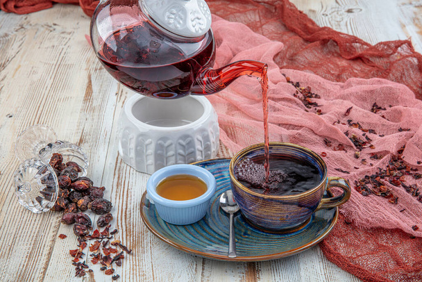 Hagebutten-Tee: Prozess-Aufguss-Tee, Teezeremonie, Tasse frisch gebrühten Hagebutten-Tee auf Holzgrund. - Foto, Bild