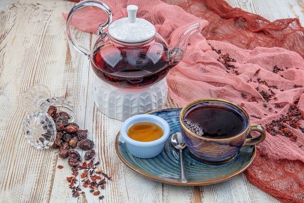 Τσάι Rosehip: Διαδικασία τσάι ζυθοποιίας, τελετή τσαγιού, Κύπελλο του φρεσκοπαρασκευασμένο τσάι rosehip σε ξύλινο φόντο. - Φωτογραφία, εικόνα