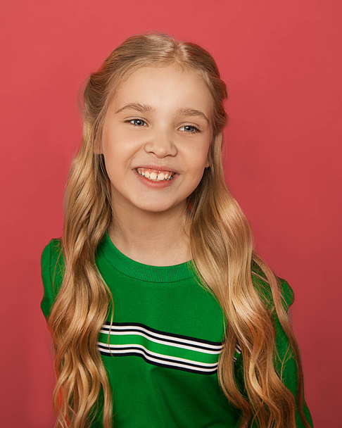 Foto der schönen blonden Mädchen von 8-10 Jahren mit blauen Augen, Haare in Locken in heller Kleidung auf einem rosa Hintergrund angeordnet glücklich lächelt und lacht. Studio Close up Portrait. Positive Emotionen - Foto, Bild