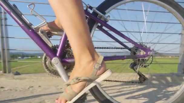 ZAMKNIJ SIĘ: nierozpoznawalna kobieta w sandałach pedałuje rowerem przez most - Materiał filmowy, wideo