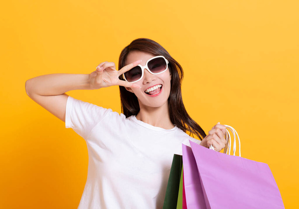 νεαρή γυναίκα με γυαλιά ηλίου και δείχνοντας τις τσάντες για ψώνια - Φωτογραφία, εικόνα