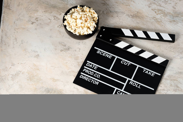 Clapper board with popcorn. Movie concept. Clapperboard on a textural background. Close-up. - Zdjęcie, obraz