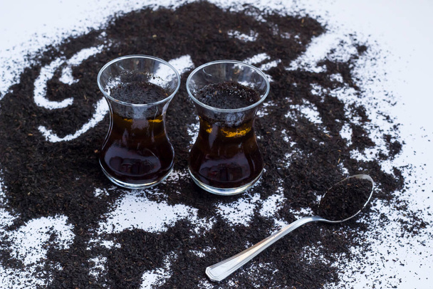 Essai naturel turc de thé sec noir est-il toute coloration alimentaire dans le thé à l'eau froide, sur la surface blanche. - Photo, image