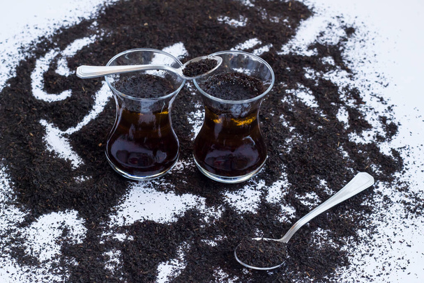 Φυσική τουρκική μαύρο ξηρό τσάι δοκιμή είναι εκεί οποιοδήποτε χρώμα των τροφίμων στο τσάι με κρύο νερό, στη λευκή επιφάνεια. - Φωτογραφία, εικόνα
