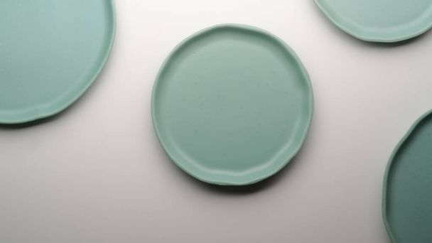 Vue du dessus des plaques en céramique turquoise maquillées et de l'espace de copie sur la table à manger blanche - Photo, image