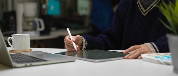 Schnappschuss einer Grafikerin, die mit digitalem Tablet und Laptop auf weißem Bürotisch arbeitet  - Foto, Bild