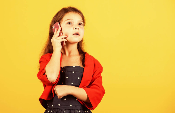 Nice talk. Happy childhood. Small child with smartphone. Cheerful little girl yellow background. Girl kid speak on smartphone. Calling friends. Smartphone for kids. Buy gadgets. Discussing news - Фото, изображение