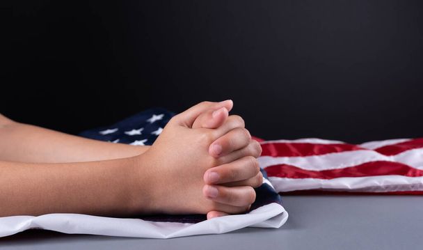 Руки женщины на флаге США. Женщина молится во время пандемии. Избирательный фокус. Копирование космического текста
.  - Фото, изображение