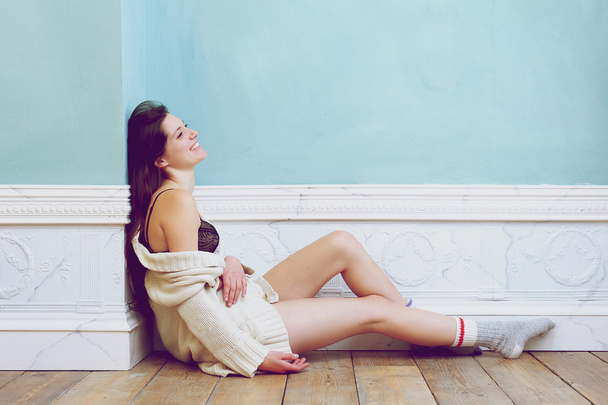 Sorrindo mulher sentada no chão sozinha com roupa interior e suéter
 - Foto, Imagem