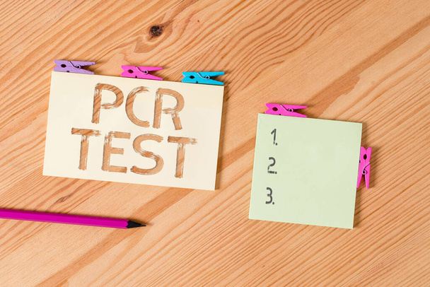 Writing note showing Pcr Test. Business photo showcasing qualitative detection of viral genome within the short seqeunce of DNA Colored clothespin papers empty reminder wooden floor background office. - Photo, Image