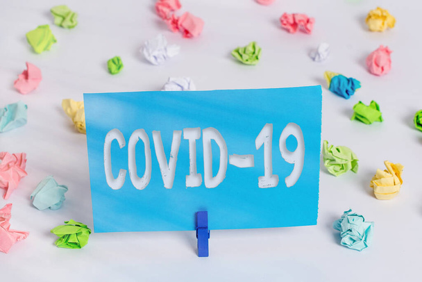 Covid19を示すメモを書く。コロナウイルスによる軽度から重度の呼吸器疾患を紹介するビジネス写真カラークランプ紙空のリマインダー白い床の服ピン. - 写真・画像