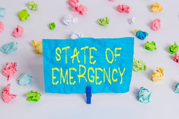 Conceptual hand writing showing State Of Emergency. Business photo showcasing acknowledging an extreme condition affecting at a national level Colored crumpled paper empty reminder white floor - Photo, Image