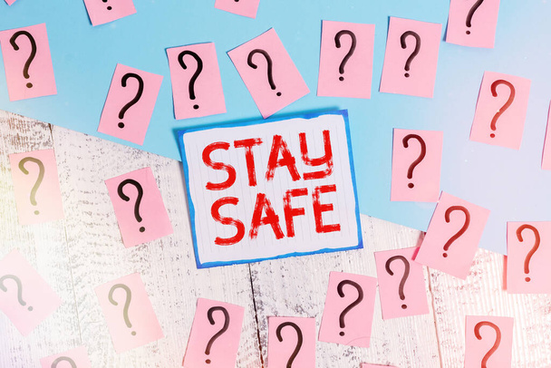 Writing note showing Stay Safe. Business photo showcasing secure from threat of danger, harm or place to keep articles Scribbled and crumbling papers with thick cardboard above wooden table. - Photo, Image