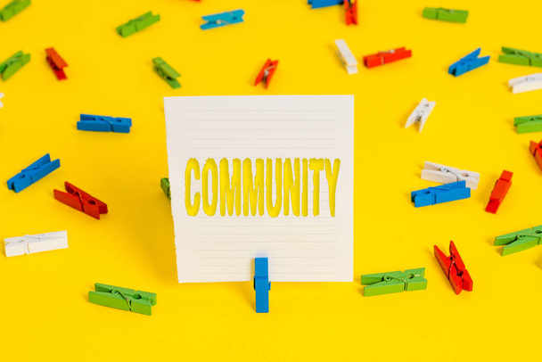 Conceptual hand writing showing Community. Business photo showcasing group of showing with a common characteristics living together Colored clothespin papers empty reminder yellow floor office. - Photo, Image