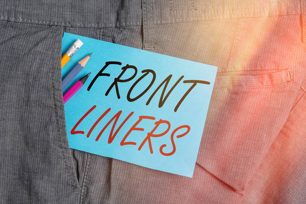 Handwriting text Frontliners. Concept meaning most important or influential position in a debate or movement. Writing equipment and blue note paper inside pocket of man work trousers. - Photo, Image