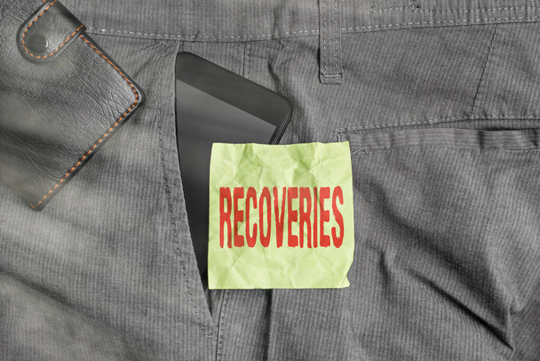 Handwriting text writing Recoveries. Concept meaning process of regaining possession or control of something lost Smartphone device inside trousers front pocket with wallet and note paper. - Photo, Image