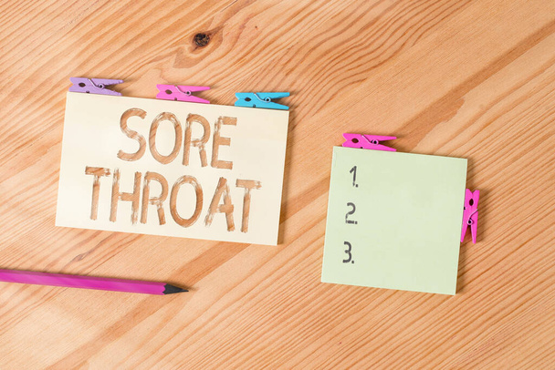 Writing note showing Sore Throat. Business photo showcasing Inflammation ot the pharynx and fauces resulted from an irritation Colored clothespin papers empty reminder wooden floor background office. - Photo, Image