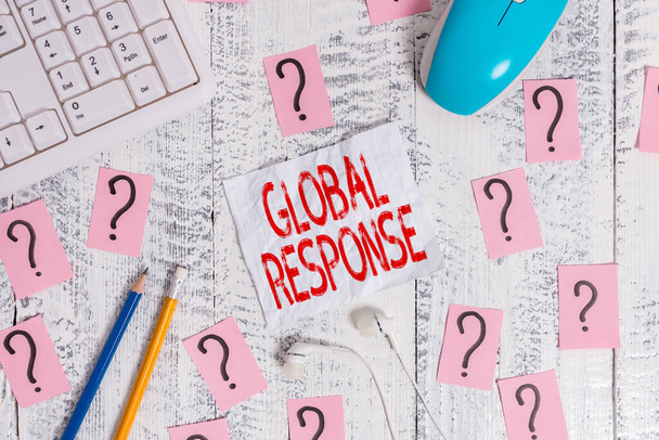 Text sign showing Global Response. Conceptual photo indicates the behaviour of material away from impact point Writing tools, computer stuff and scribbled paper on top of wooden table. - Photo, Image