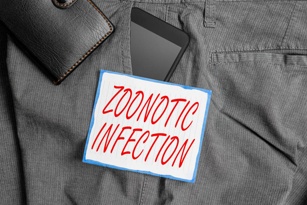 Text sign showing Zoonotic Infection. Conceptual photo communicable disease transmitted by a non viral agent Smartphone device inside trousers front pocket with wallet and note paper. - Photo, Image