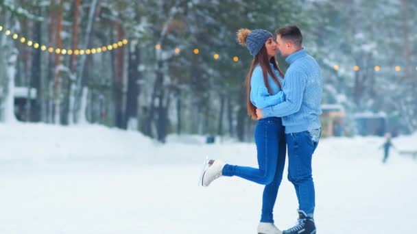 schattig paar in blauw truien knuffels en kussen op schaatsbaan - Video