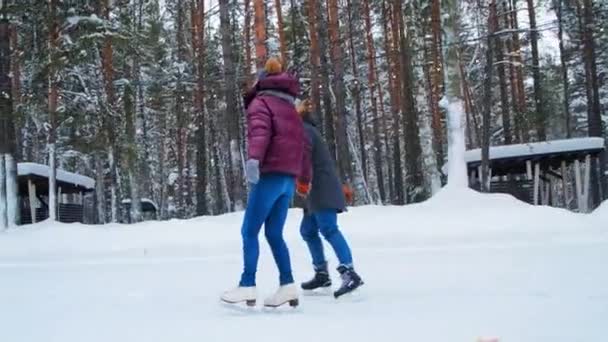 dziewczyna w fioletowej kurtce i facet łyżwy łączące ręce wzdłuż pierścienia - Materiał filmowy, wideo