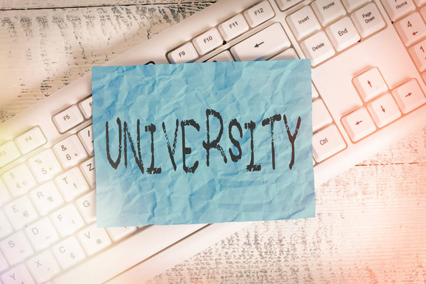 Text sign showing University. Conceptual photo an educational institution designed to teach and investigate White keyboard office supplies empty rectangle shaped paper reminder wood. - Photo, Image
