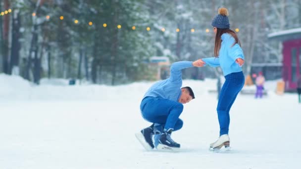 meisje helpt vriend opstaan van ijs op schaatsbaan - Video