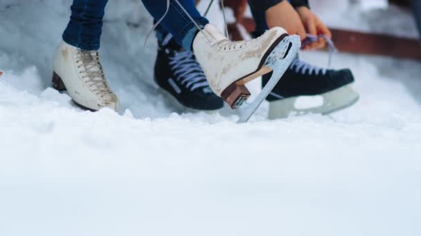 Mädchen und Mann schnüren Eiskunstläufer zum Ausruhen auf offener Eisbahn - Filmmaterial, Video