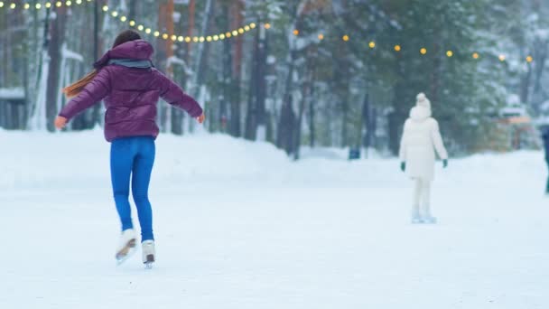jonge vrouw in paarse jas draait op schaatsen op de ijsbaan - Video