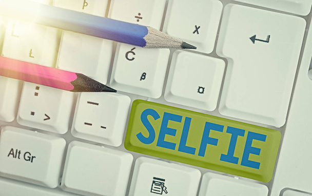 Conceptual hand writing showing Selfie. Business photo text taken by oneself using a digital camera for posting on social network White pc keyboard with empty note paper above white key copy space. - Photo, Image