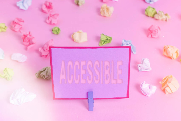 Writing note showing Accessible. Business photo showcasing defined as something you can get to use or obtain or reach Colored crumpled papers empty reminder pink floor background clothespin. - Photo, Image