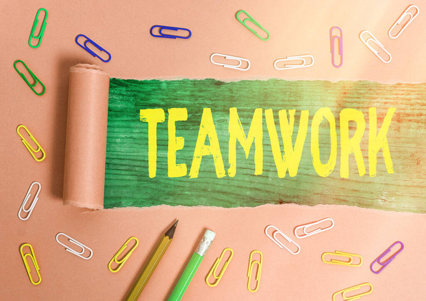 Writing note showing Teamwork. Business photo showcasing the group s is collaborative effort to accomplish a common goal Rolled ripped torn cardboard above a wooden classic table. - Photo, Image