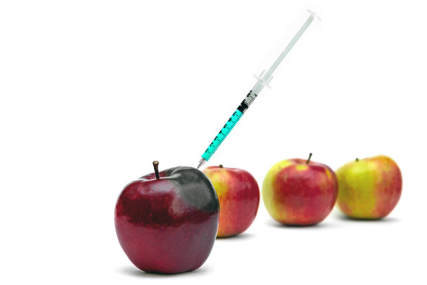Syringe injection into a red apple. Genetic modified foods, gmo. isolated on white background. - Фото, изображение