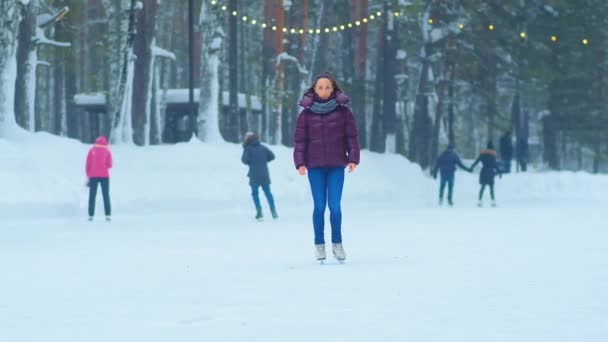 vrouw in jas staat op ijs van outdoor park schaatsbaan - Video