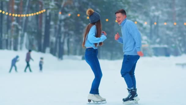 podekscytowany mężczyzna tańczy z dziewczyną na łyżwach na świeżym powietrzu - Materiał filmowy, wideo