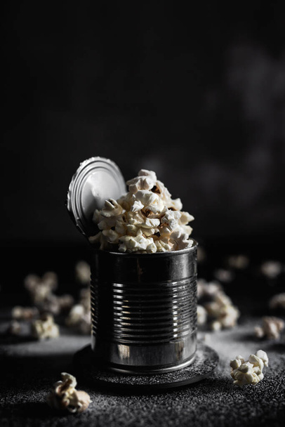 Salted popcorn in a steel tin on dark background, moody photo - Fotografie, Obrázek