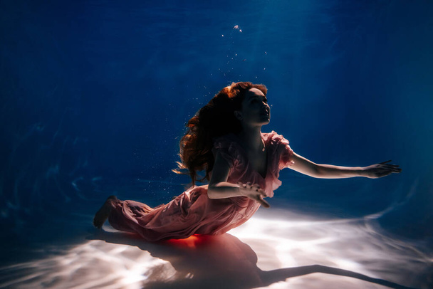 Nainen vaaleanpunainen mekko Uima tumma vedenalainen allas - Valokuva, kuva