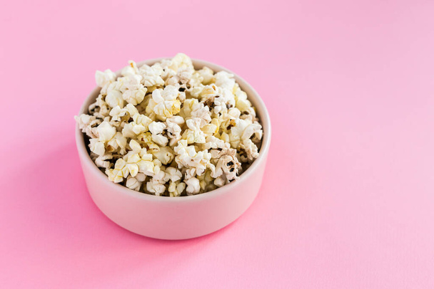 Popcorn in a pink bowl on pink background - Fotó, kép