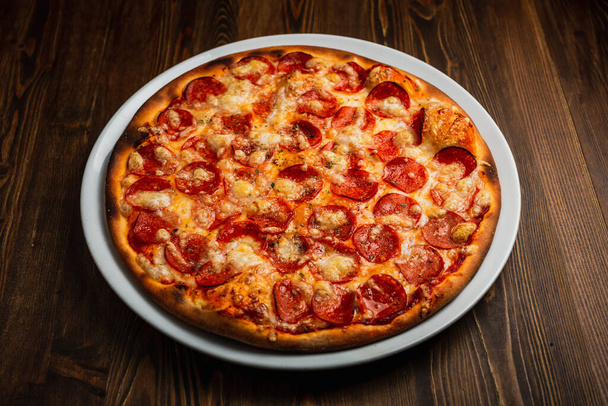 Pepperoni pizza with a nice crust, wooden background, low key - Foto, imagen