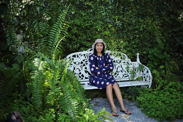 Mulher sentada no jardim com plantas verdes
 - Foto, Imagem