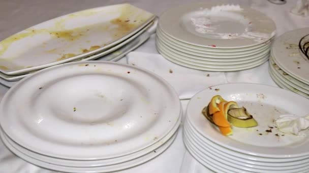 Pöydällä on paljon likaisia astioita, jotka on pinottu juhlan jälkeen.. - Materiaali, video