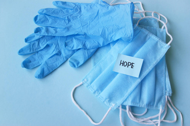 A three-layer medical mask with rubber ear straps and blue stiker with the word hope. The concept of medicine. Hope. Stay home, stay safe. - Photo, Image