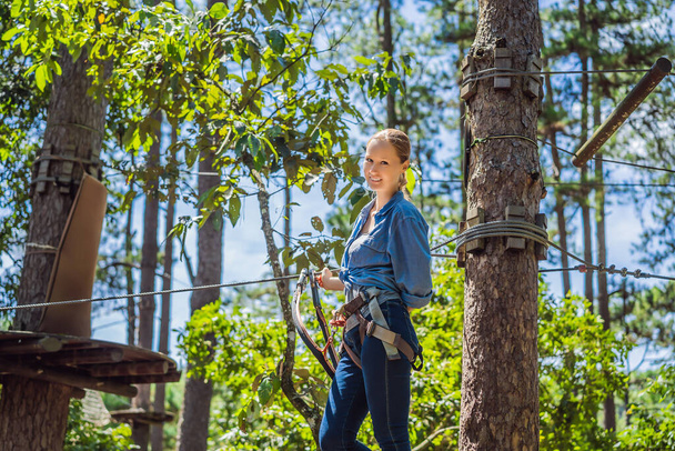 Young attractive woman in adventure rope park in safety equipment - Zdjęcie, obraz