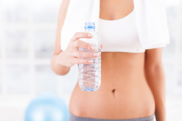 Woman in sports clothing holding a bottle with water - Фото, изображение