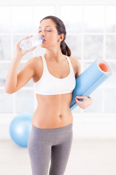 Woman in sports clothing drinking water - Фото, зображення