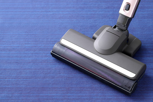 Head of modern vacuum cleaner on blue carpet background. Close up. - Photo, Image